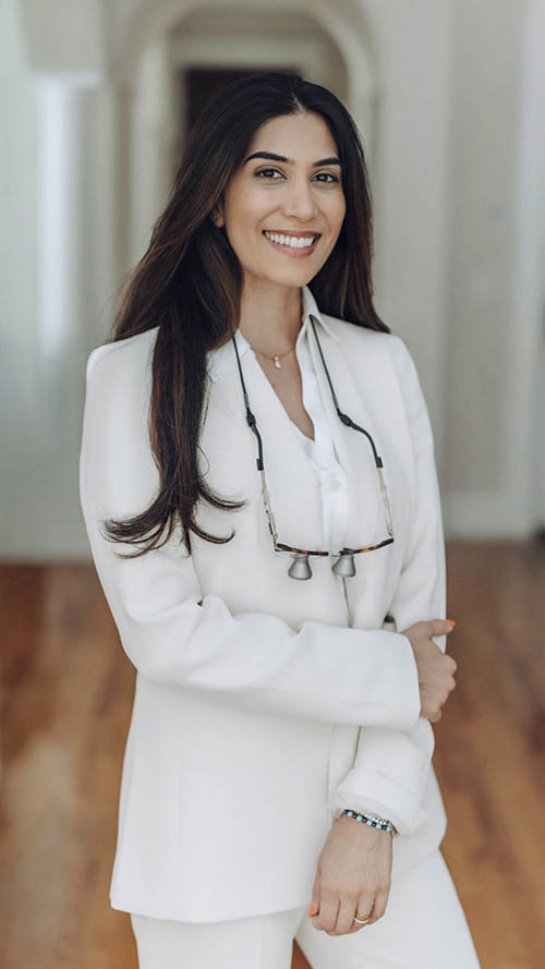 The image features a woman wearing a white business suit, posing indoors with a confident smile.